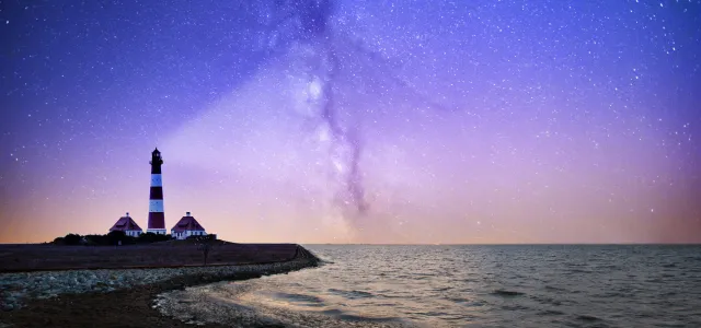 white and red lighthouse near bodies of water at night by Robert Wiedemann courtesy of Unsplash.