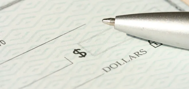 a pen sitting on top of a cheque paper by Money Knack courtesy of Unsplash.
